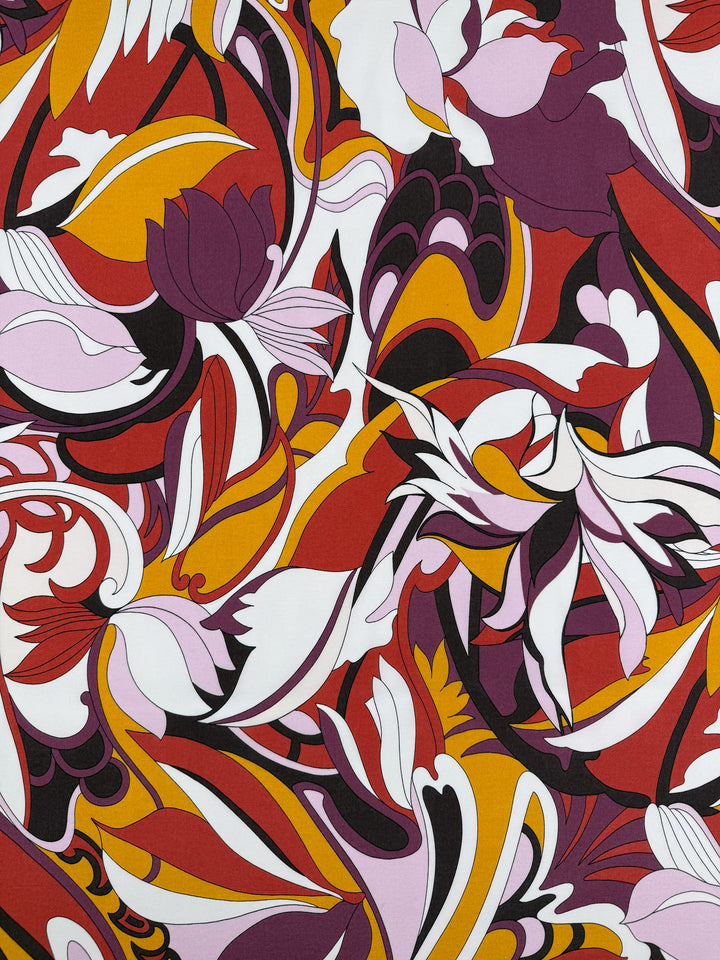 Super Cheap Fabrics' Printed Viscose - Fantasia (145cm) features a vibrant abstract floral pattern with swirling red, yellow, orange, purple, black, and white shapes on lightweight viscose, evoking overlapping flowers in a dynamic composition.