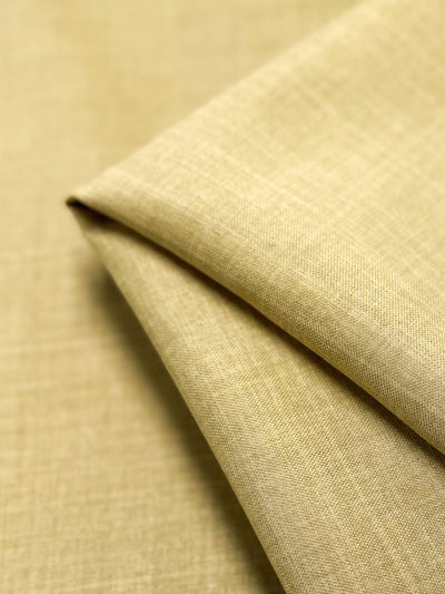 A close-up of Twill Suiting - Cocoon - 150cm by Super Cheap Fabrics, featuring beige textured fabric with a subtle diagonal weave, neatly folded to highlight its clean lines and soft, versatile material.