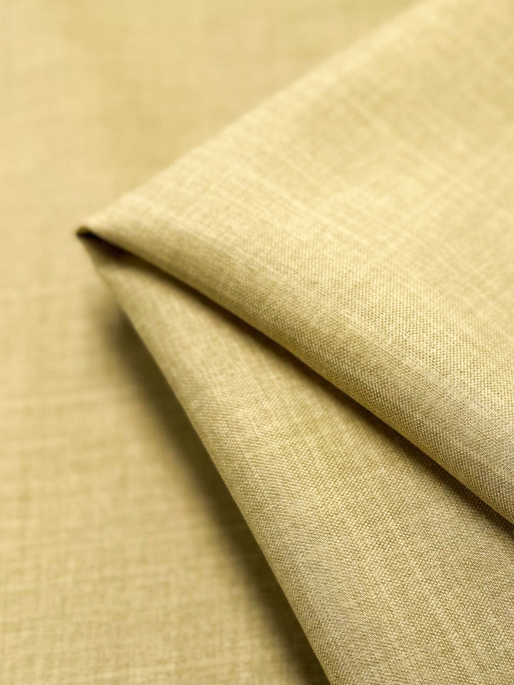 A close-up of Twill Suiting - Cocoon - 150cm by Super Cheap Fabrics, featuring beige textured fabric with a subtle diagonal weave, neatly folded to highlight its clean lines and soft, versatile material.