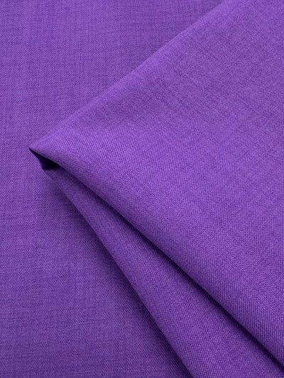 Close-up of folded Twill Suiting - Amethyst Orchid (150cm) by Super Cheap Fabrics, showing its smooth, slightly textured surface, even color, and fine diagonal weave in a vibrant purple shade.