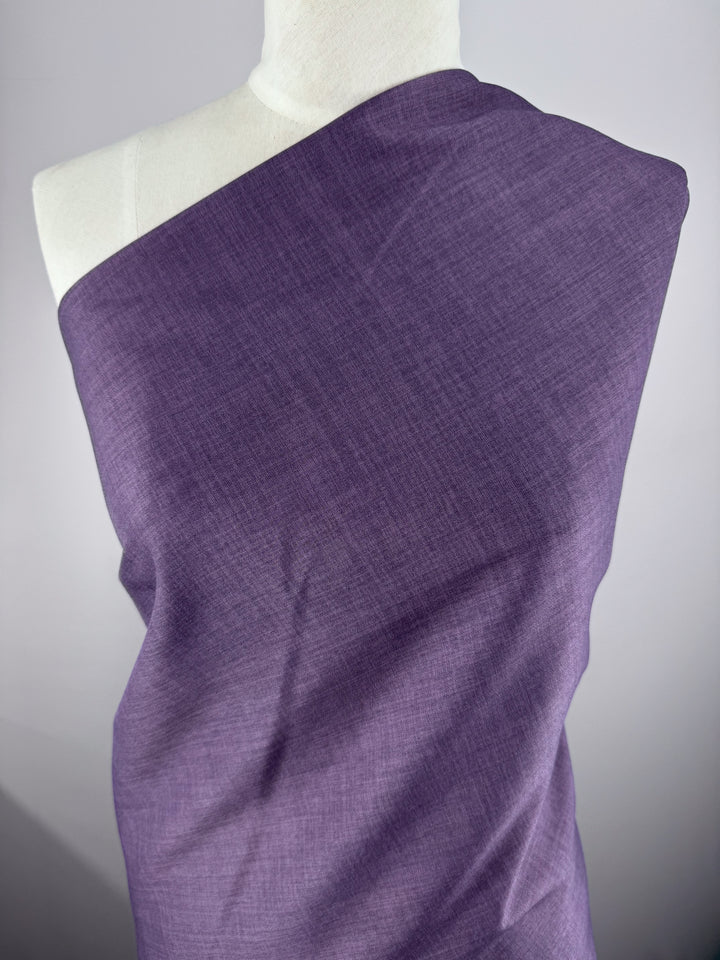 A mannequin showcases Super Cheap Fabrics' Twill Suiting - Wineberry - 150cm, elegantly draped over one shoulder and wrapped around the torso, highlighting its versatility against a plain light gray background.