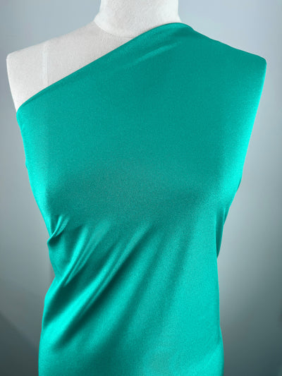 A mannequin displays Super Cheap Fabrics' Nylon Lycra - Columbia (154cm) in vibrant teal, highlighting its smooth texture and bold color against a plain backdrop.