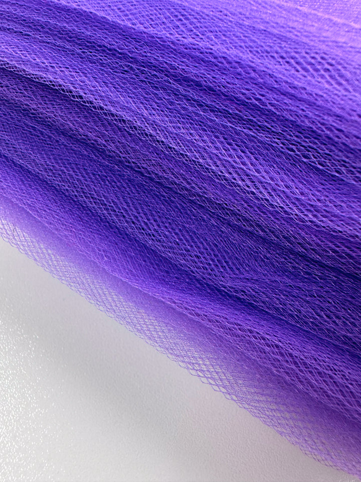 Close-up of Super Cheap Fabrics' Soft Tulle - Purple - 150cm, featuring fine mesh layers in light to dark purple hues. Ideal for bridal veils and lightweight projects, it displays a smooth surface with a beautiful gradient effect.