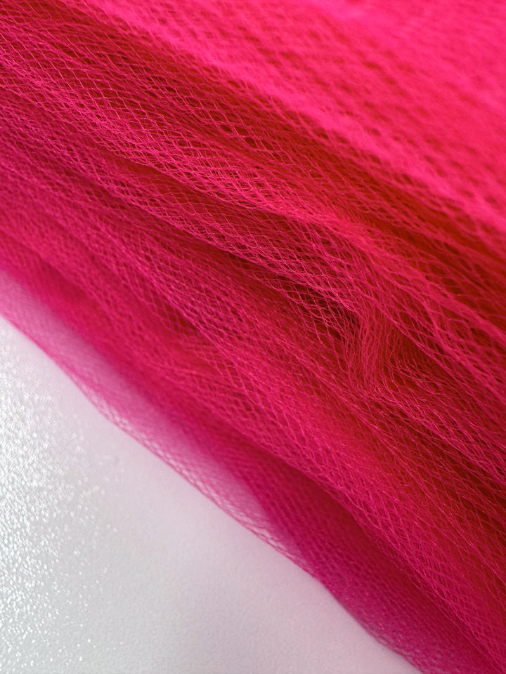 Close-up of Super Cheap Fabrics' Soft Tulle - Teaberry (150cm), showcasing its vibrant pink hue and fine mesh texture, ideal for lightweight projects like bridal veils.