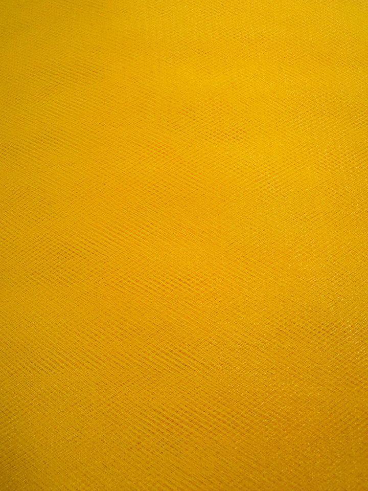 A close-up of Soft Tulle - Yellow - 150cm by Super Cheap Fabrics, featuring a textured surface with subtle diagonal lines and a slightly uneven look, reminiscent of the sheer, lightweight material often used in bridal veils.