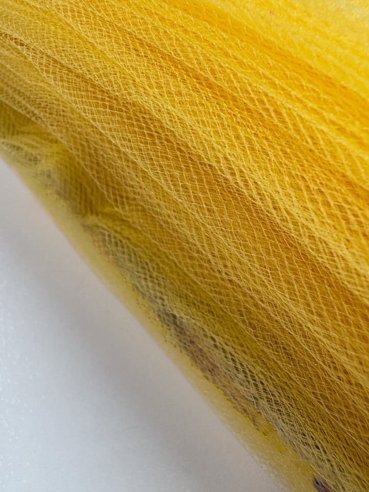 Close-up of Super Cheap Fabrics’ Soft Tulle - Yellow - 150cm shows fine, crisscrossing threads for a textured look—ideal for lightweight, sheer bridal veils.