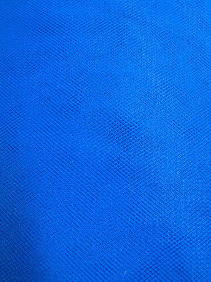 Close-up of Soft Tulle - Royal - 150cm by Super Cheap Fabrics, featuring a textured blue surface with a subtle grid pattern, evoking the delicate look and depth typical of tulle used in bridal veils and craft projects.