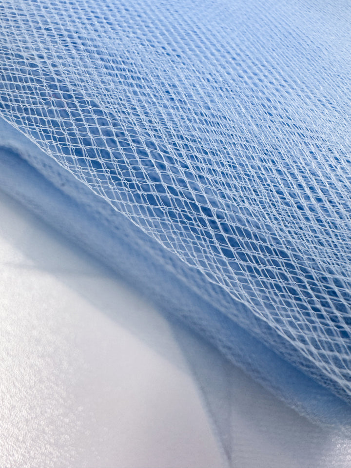 Close-up of Super Cheap Fabrics’ Soft Tulle - Spun Sugar (150cm), featuring light blue, diamond-patterned netting layered over white. Its fine texture is perfect for craft projects or delicate bridal veils.