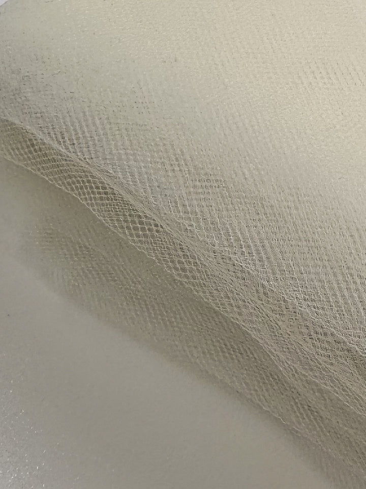 A close-up of Soft Tulle - Cream - 150cm by Super Cheap Fabrics shows the delicate, net-like texture and translucent quality that makes this lightweight fabric ideal for bridal veils and other elegant creations.