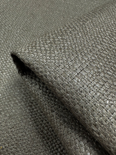 Close-up of folded Upholstery Basket Weave - Dorian Putty fabric by Super Cheap Fabrics. It features a textured, thick basket weave pattern in light and dark grey tones, offering a slightly reflective surface for striking contrast. Width: 145cm.
