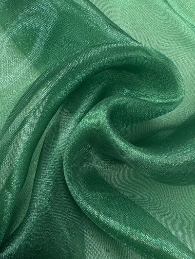 Close-up of Super Cheap Fabrics’ Organza - Juniper - 150cm: sheer, shimmery green polyester with soft folds and a smooth texture. This lightweight fabric catches the light, ideal for elegant evening gowns.