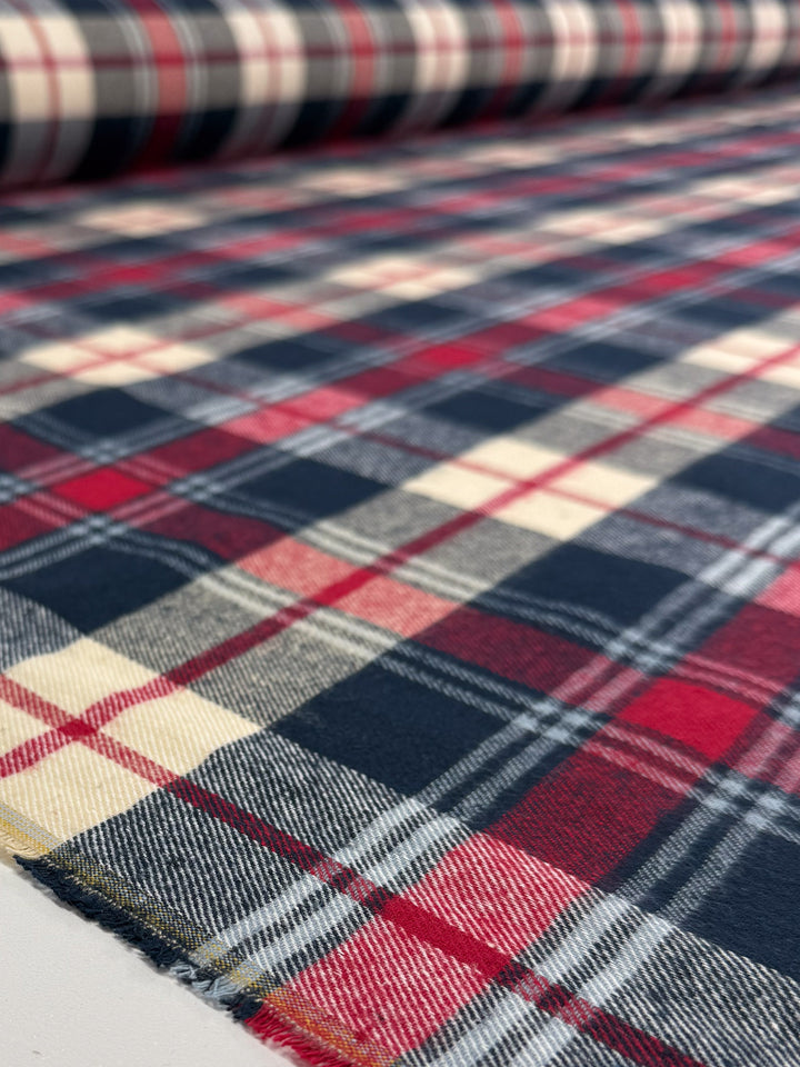 A close-up of Super Cheap Fabrics' Flannel Tartan - Highland (145cm) shows its classic Scottish-style check in red, navy blue, and cream stripes on soft cotton flannel.