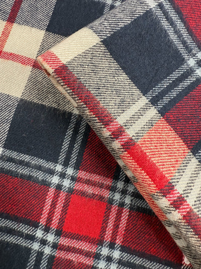 Close-up of Super Cheap Fabrics’ Flannel Tartan - Highland (145cm), a medium-weight cotton fabric with a red, black, cream, and gray plaid pattern and classic Scottish style.