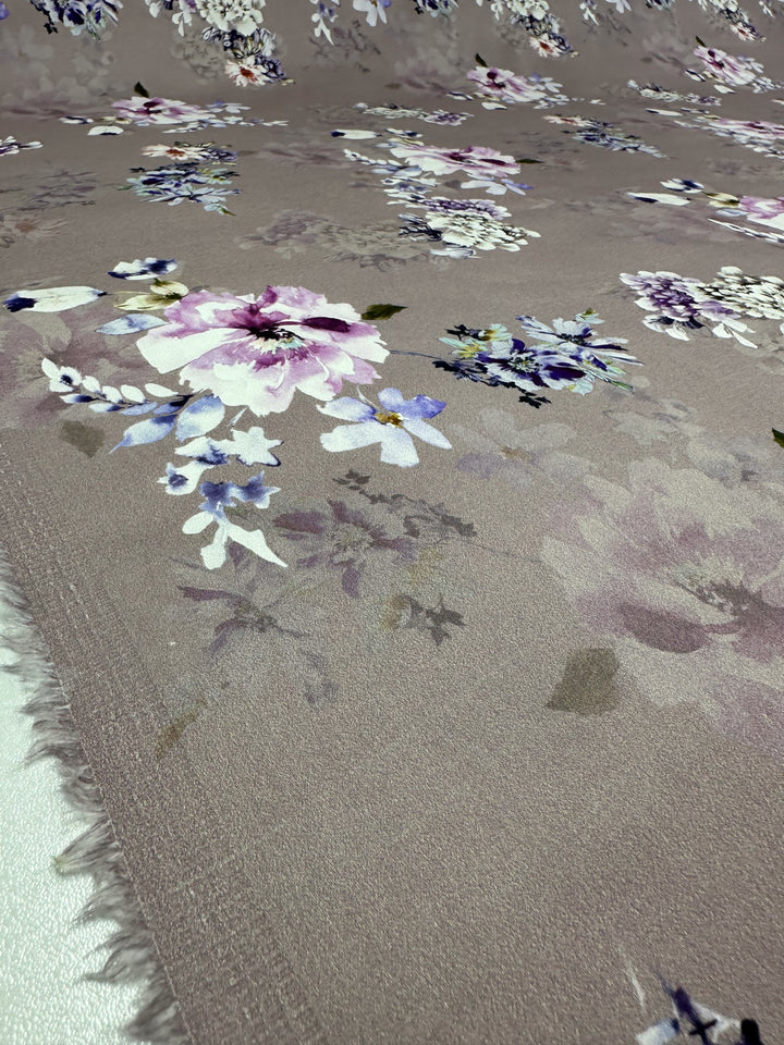 A detailed look at Super Cheap Fabrics' Cotton Sateen - Shadow Rose - 120cm reveals a lightweight floral design with purple, pink, and white flowers on a taupe background. The fabric edge appears on the left side.