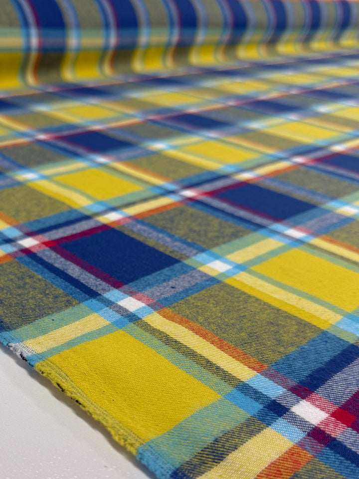 A close-up of Super Cheap Fabrics’ Flannel Plaid - Sunshine Heritage (145cm): a medium weight cotton with yellow plaid and blue, white, red, and green stripes in a bold checkered design, displayed flat.