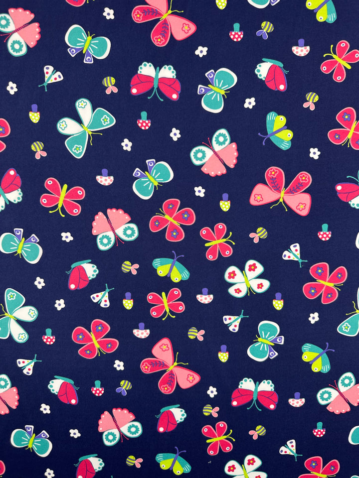 The Printed Delustered Satin - Butterfly by Super Cheap Fabrics features a dark blue background adorned with vibrant pink, green, blue, and yellow butterflies and delicate small flowers, reminiscent of elegant satin pieces.