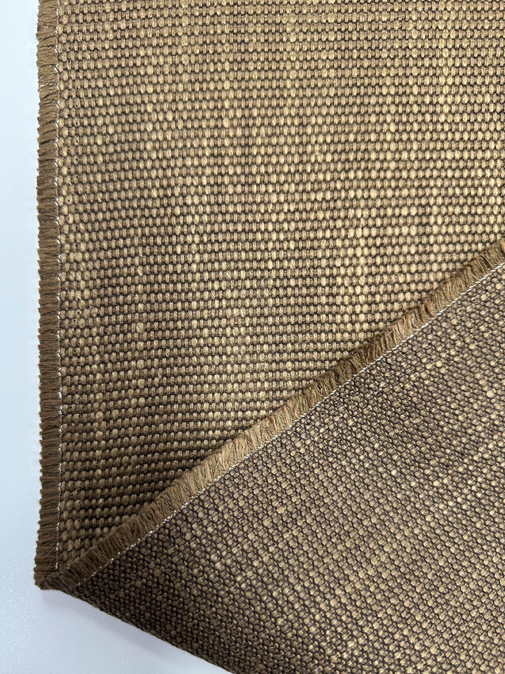 A close-up of two overlapping pieces of Super Cheap Fabrics' Grid Upholstery - Yari 014 (147cm), an earthy brown heavyweight woven fabric with a fringed edge, displayed on a white surface.