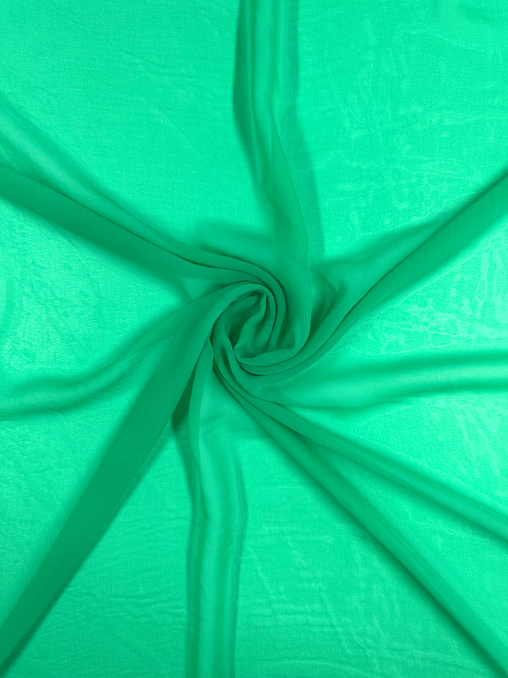 The Hi-Multi Chiffon - Blarney by Super Cheap Fabrics is a green, lightweight fabric with a spiral pattern. Its slightly sheer, smooth texture creates soft folds radiating outward for a dynamic visual effect.