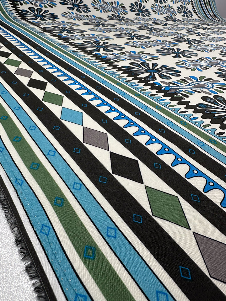 Designer Rayon - Dance by Super Cheap Fabrics is a lightweight 145cm rayon fabric with bold black, white, green, and gray diamond rows, blue accents, floral motifs, and decorative blue and black floral borders.