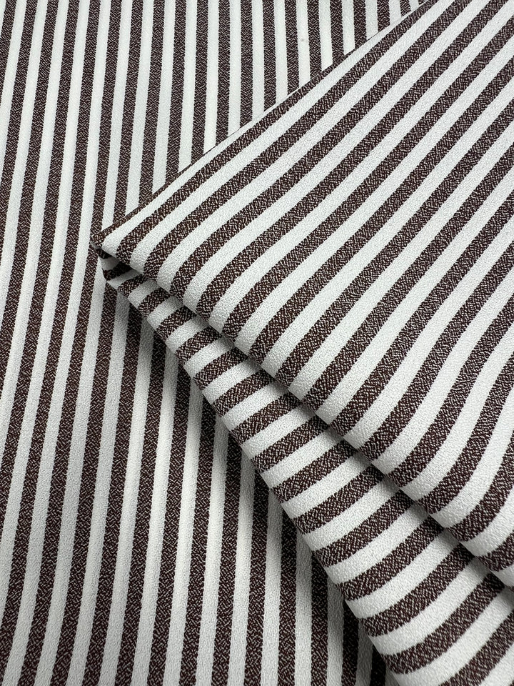 Close-up of Striped Crepe - Fondue Fudge by Super Cheap Fabrics, 150cm wide. Lightweight polyester with brown and white vertical stripes and textured surface, perfect for chic eveningwear.