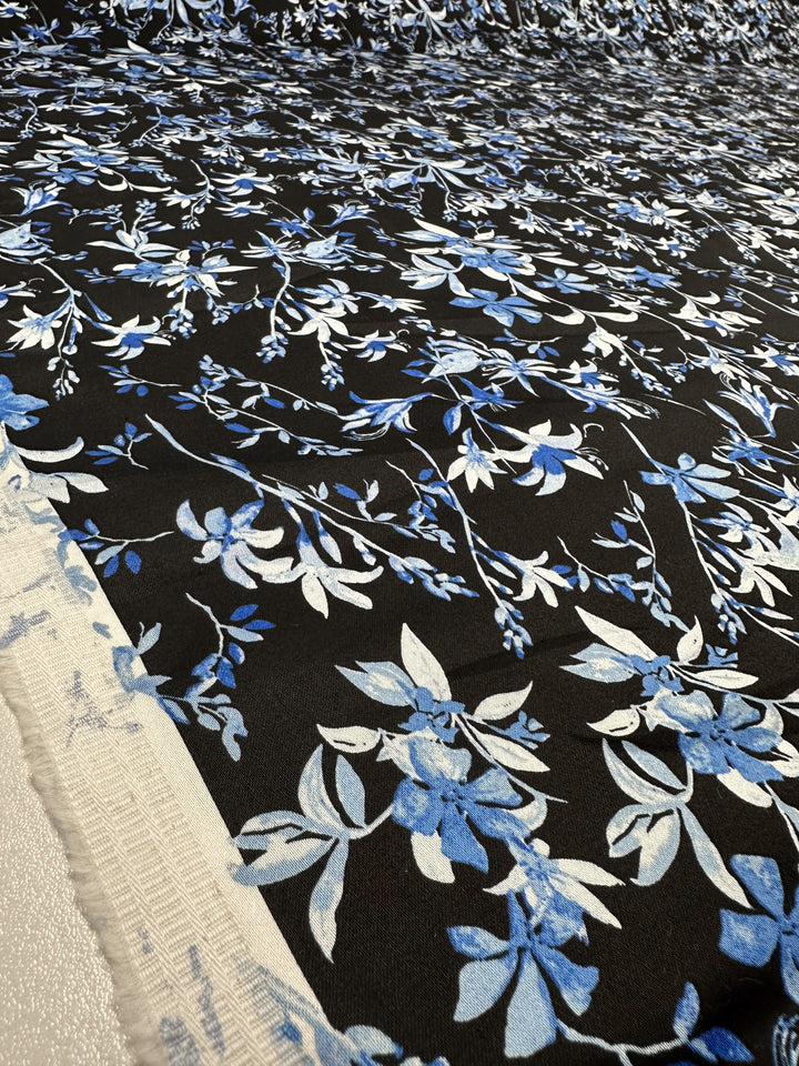 A close-up of Cotton Sateen - Blue Lotus by Super Cheap Fabrics shows its blue and white floral pattern on medium-weight black blue fabric, spread out with the selvage edge visible on the left. Width: 146cm.