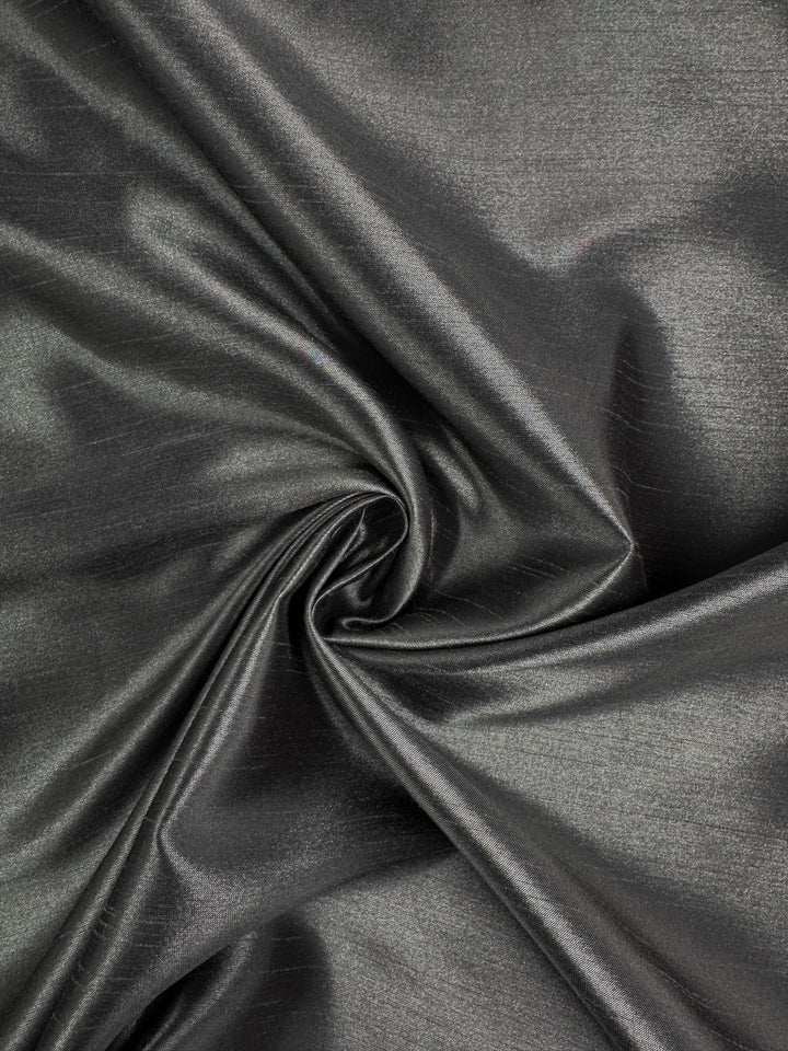 Shantung Satin - Charcoal by Super Cheap Fabrics is a metallic gray satin fabric, 150cm wide, with a smooth texture and elegant folds that catch the light for gentle highlights.