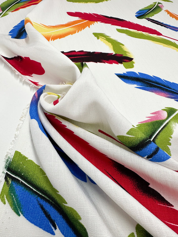 Super Cheap Fabrics' Bamboo Rayon - Feather White (150cm) is a lightweight, beginner-friendly fabric with a vibrant feather print in red, blue, green, yellow, and orange—ideal for creative sewing projects.