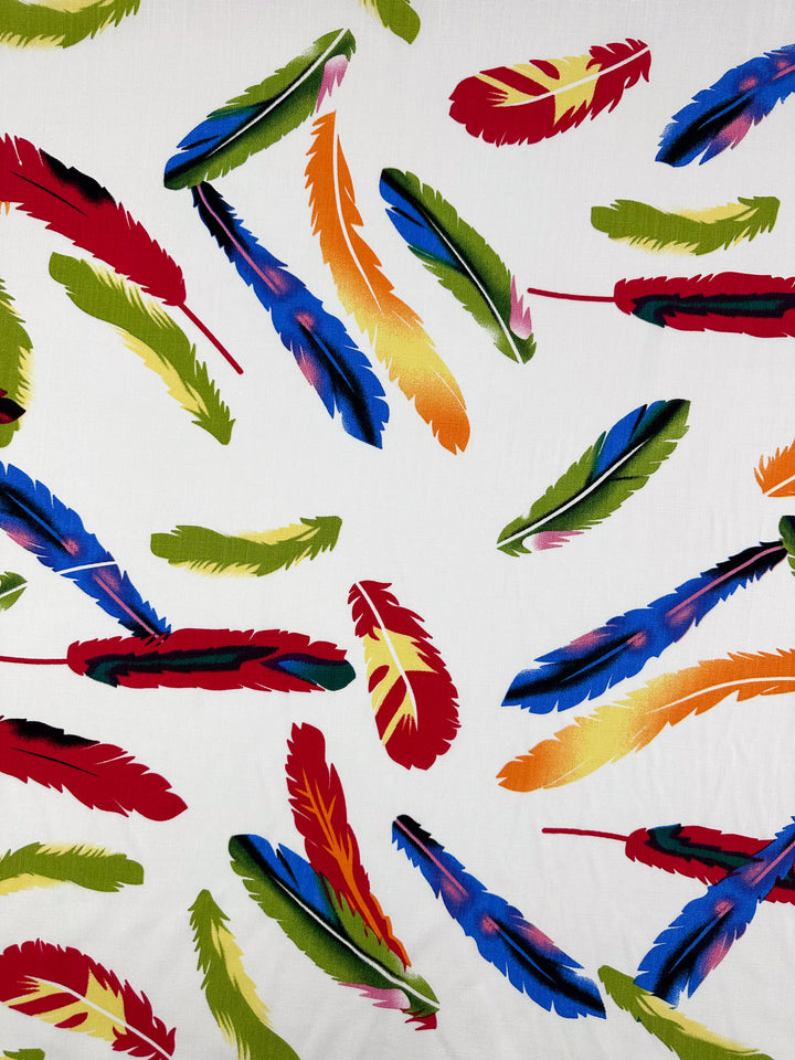 Bamboo Rayon - Feather White by Super Cheap Fabrics features a white background with vibrant red, green, blue, yellow, and orange feathers—perfect for beginner-friendly sewing or creating lightweight projects. Width: 150cm.