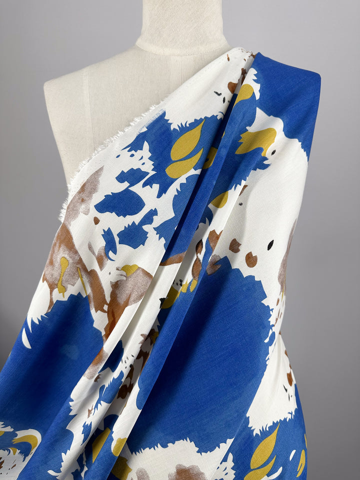 A mannequin displays Super Cheap Fabrics' Bamboo Rayon - Splash (150cm), featuring lightweight fabric with an abstract blue, white, yellow, and brown splash pattern on a light gray background.