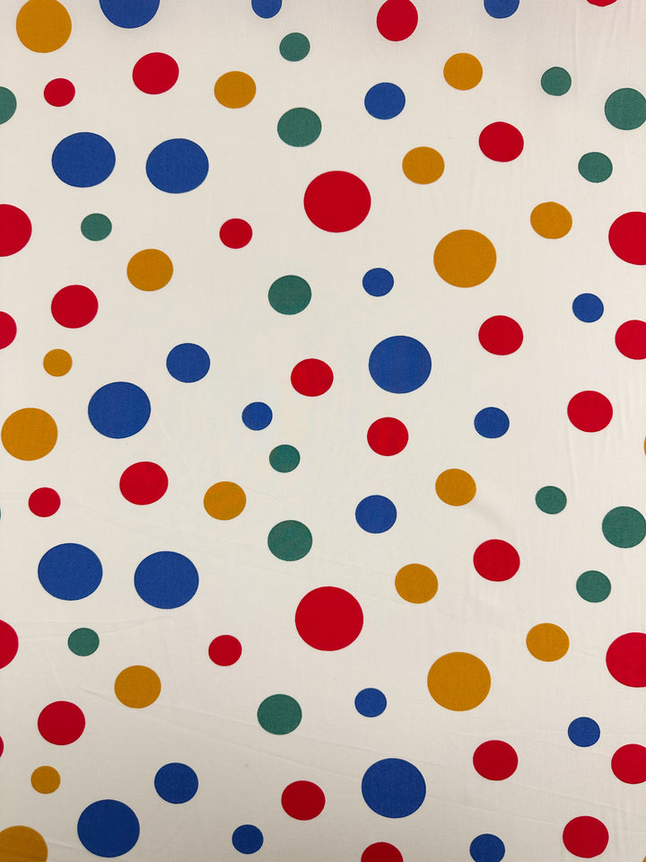 Designer Rayon - Pop of Colour by Super Cheap Fabrics features a white background with evenly spaced red, blue, yellow, and green polka dots. This 145cm versatile fabric is perfect for creative projects.