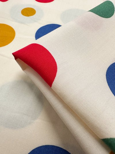 Designer Rayon - Pop of Colour by Super Cheap Fabrics is a 145cm cream fabric with bold red, blue, yellow, and green polka dots—ideal for bringing vibrant style to any versatile collection.