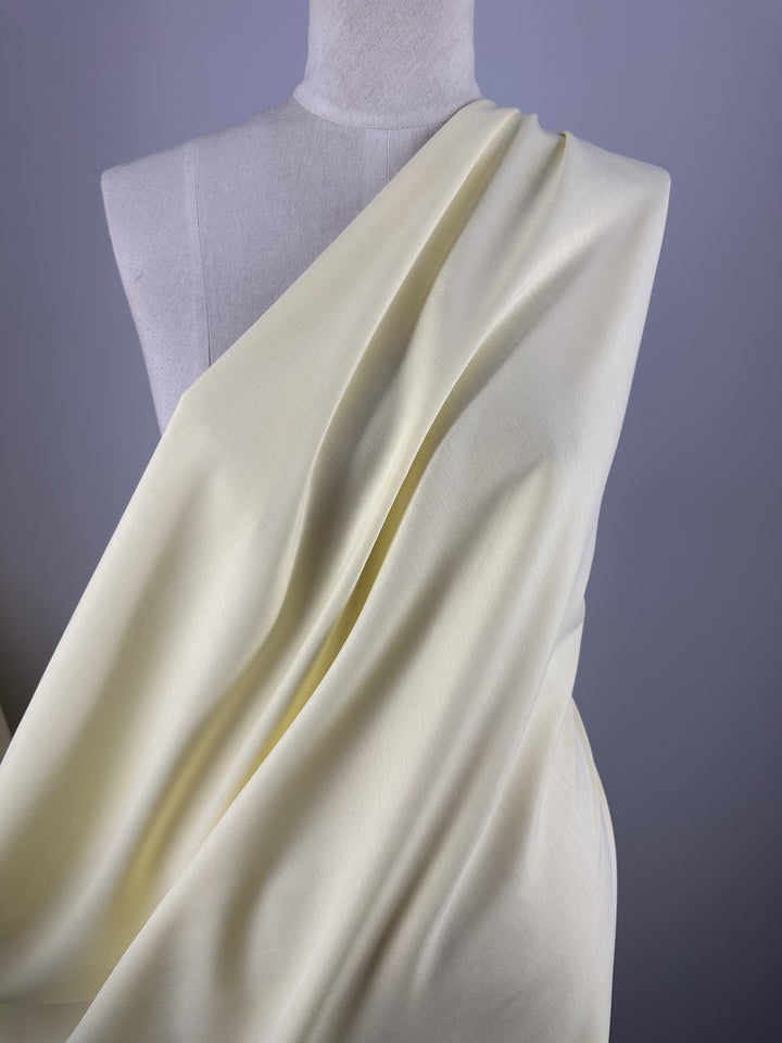 A mannequin displays Super Cheap Fabrics’ Oxford Cotton - Lemon (146cm), draped diagonally across the torso against a plain, light gray background.