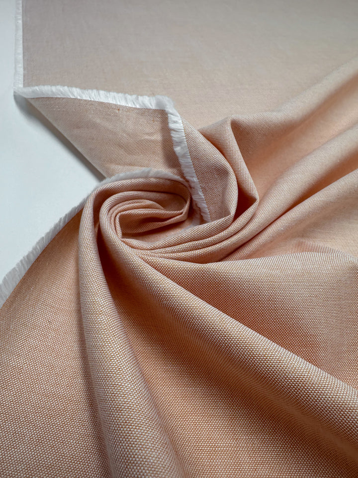 A close-up of Oxford Cotton - Sunburst from Super Cheap Fabrics shows its light peach hue, subtle texture, and white selvage edge. Fabric width: 146cm.