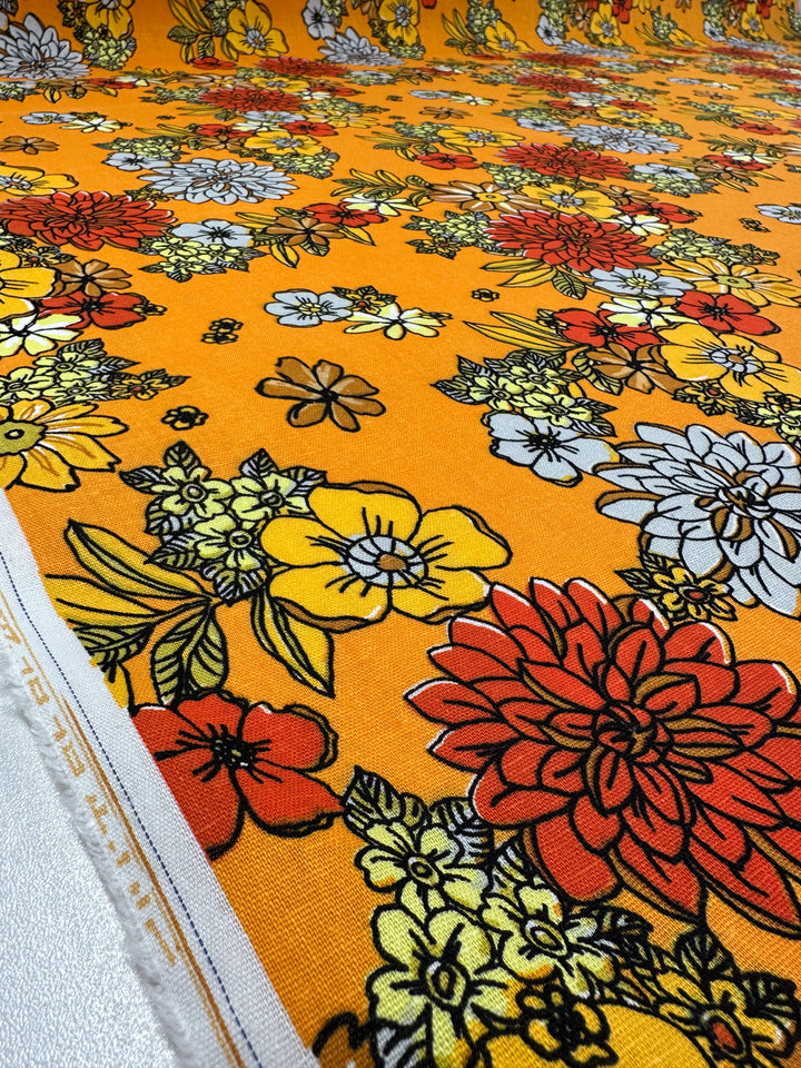 Super Cheap Fabrics' Printed Linen Blend - Golden Garden (128cm) features a vibrant floral design in orange, red, yellow, and white with green leaves on medium-weight linen for a bold, colorful look.