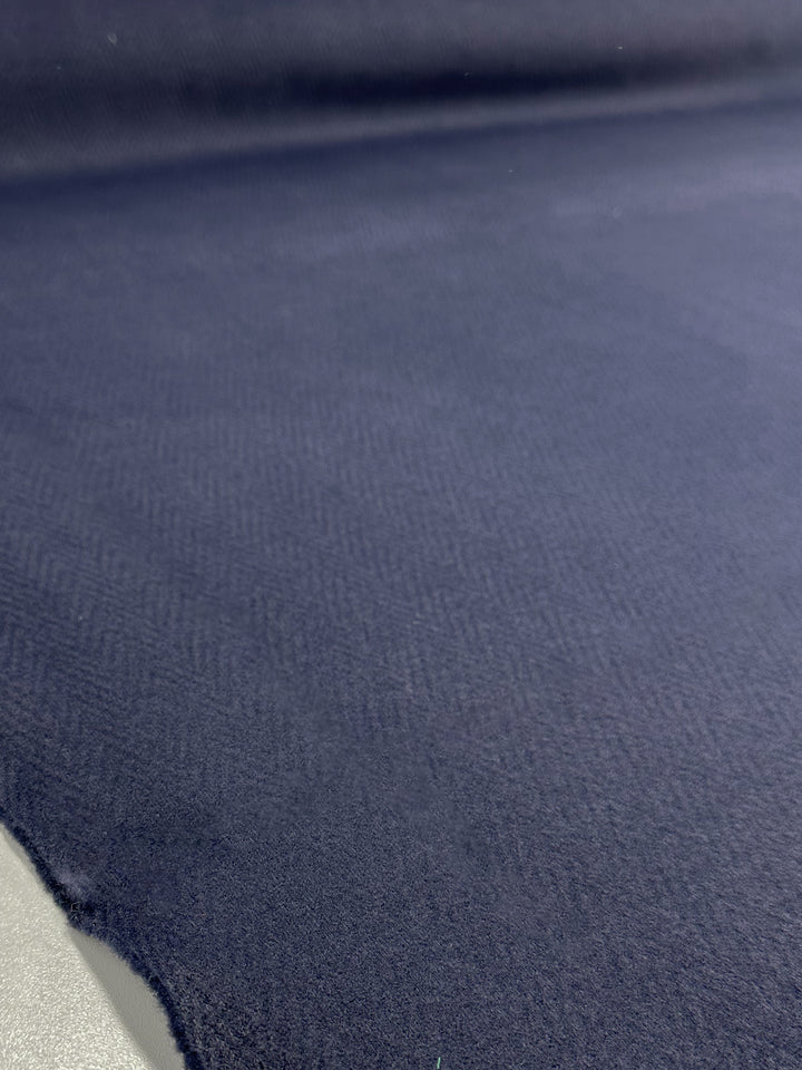 A close-up of Super Cheap Fabrics' Pressed Fleece Coating - Chevron (160cm) in dark blue, showing its slight texture and unfinished edge—ideal for medium weight projects.