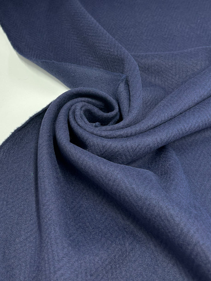 A close-up of Soft Navy Pressed Fleece Coating - Chevron by Super Cheap Fabrics, 160cm wide, featuring a subtle herringbone pattern. This medium-weight fabric provides elegance and versatility for many projects.