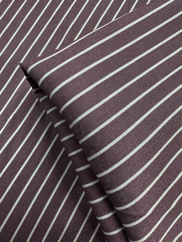 A close-up of Chambray - Grape Shake by Super Cheap Fabrics (150cm), showing its folded texture and diagonal white stripes—this lightweight fabric is ideal for creating stylish, breathable garments.