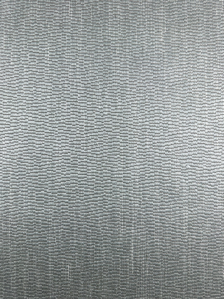 Close-up of Super Cheap Fabrics’ Cut Pile Jacquard Upholstery in Oscar Gunmetal (142cm), showing a textured metallic silver surface with a repeating rectangular pattern that creates subtle light and shadow effects.