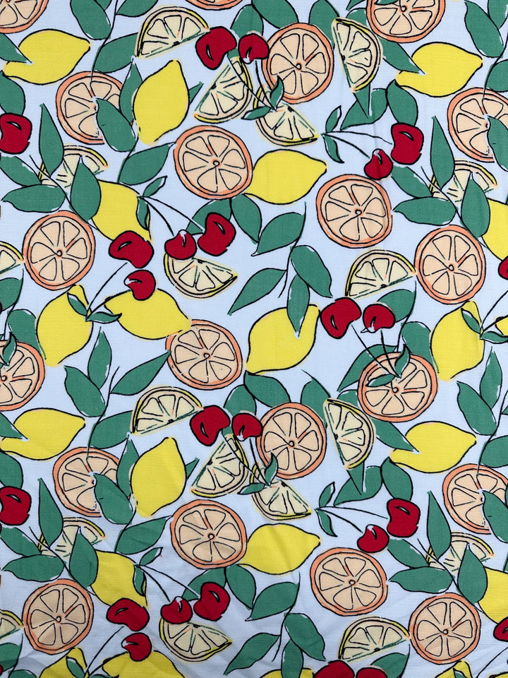 Super Cheap Fabrics' Printed Linen Blend - Citrus Crush (134cm) features a lively mix of lemons, oranges, cherries, and green leaves on a light background—ideal for summery upholstery or vibrant jackets.