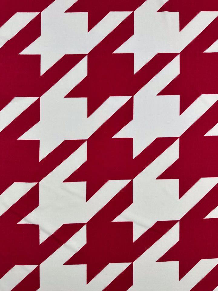 Super Cheap Fabrics' Printed Lycra - Bold Bite (154cm) features a red and white houndstooth with large, diagonal geometric shapes in a repeating jagged design on medium-weight polyester/spandex.