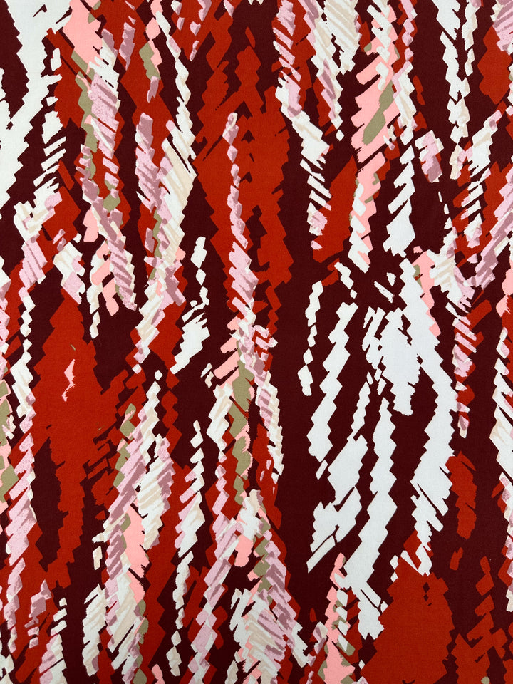 Crimson Crush Printed Lycra by Super Cheap Fabrics features jagged, zigzag brushstrokes in red, pink, white, and olive green on 150cm medium-weight fabric—ideal for standout style and movement.