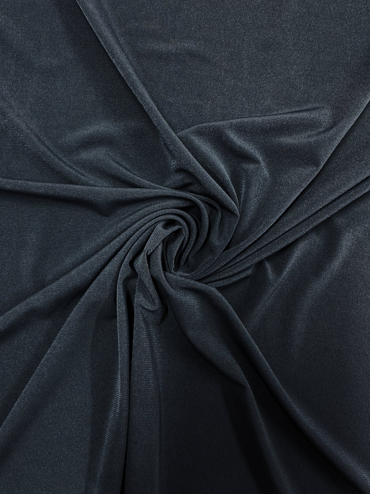 Super Cheap Fabrics' ITY Knit - Dark Slate (150cm) features a dark gray polyester spandex with a subtle sheen, gathered into soft folds and radiating pleats that emphasize its smooth, flowing texture.