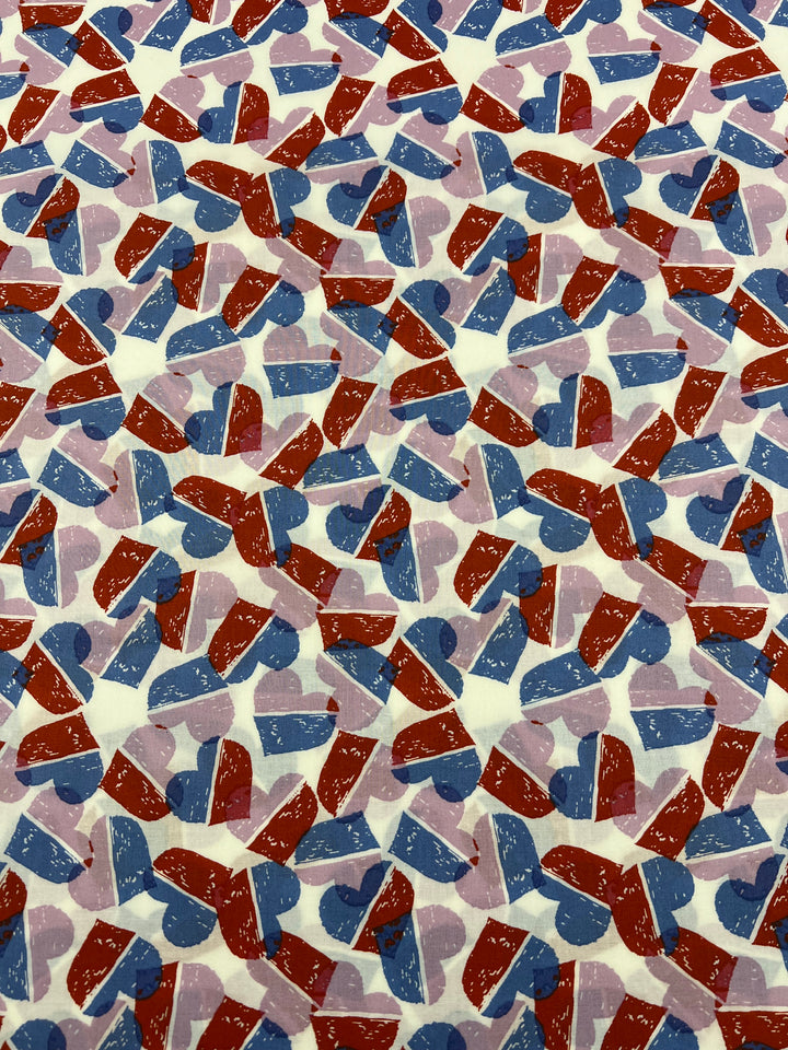 Super Cheap Fabrics’ Printed Cotton - Berry Candy Hearts - 148cm features overlapping red, blue, and light purple hearts on white 100% cotton fabric, arranged in various directions for a vibrant, abstract textile design.