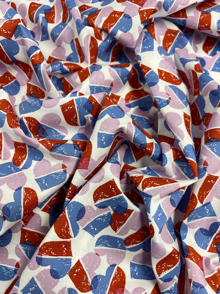 Super Cheap Fabrics’ Printed Cotton - Berry Candy Hearts - 148cm features a playful heart pattern in red, blue, and light purple on white 100% cotton. Overlapping hearts create a lively and colorful textile design.