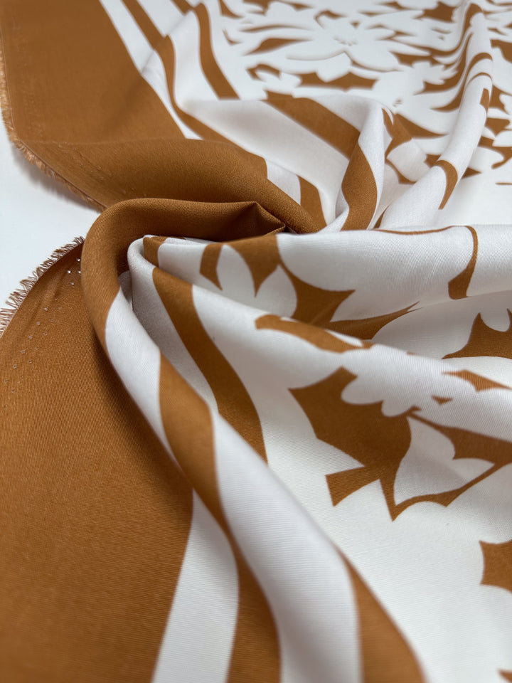 A close-up of Designer Rayon - Clay Fade (145cm) by Super Cheap Fabrics, featuring smooth brown and white floral and geometric patterns—perfect for vibrant, detailed creations.