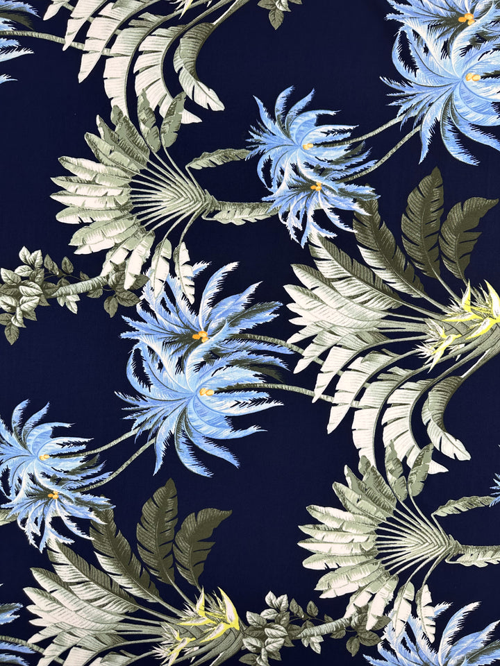 Printed Lycra - Islander Drift by Super Cheap Fabrics features large blue and white tropical flowers with green and beige leaves on dark navy, printed on soft polyester spandex stretch fabric. Ideal for vibrant, bold creations. Width: 150cm.
