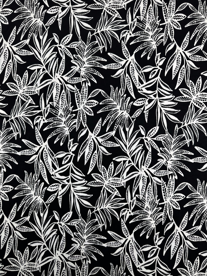 Textured Lycra - Shadow Fern by Super Cheap Fabrics: Smooth 150cm lycra with a black background and detailed white fern pattern, creating a dense, tropical effect.