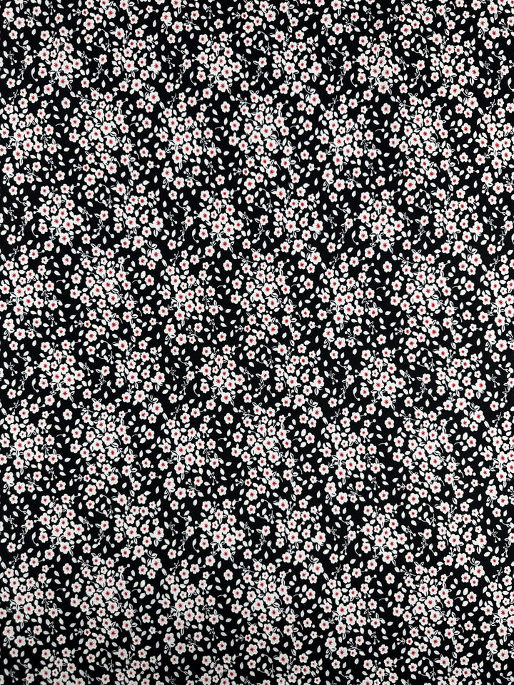 Textured Lycra - Sugar Pollen by Super Cheap Fabrics features small light pink and white flowers with green leaves on a black background, printed on medium weight polyester spandex, 150cm wide.