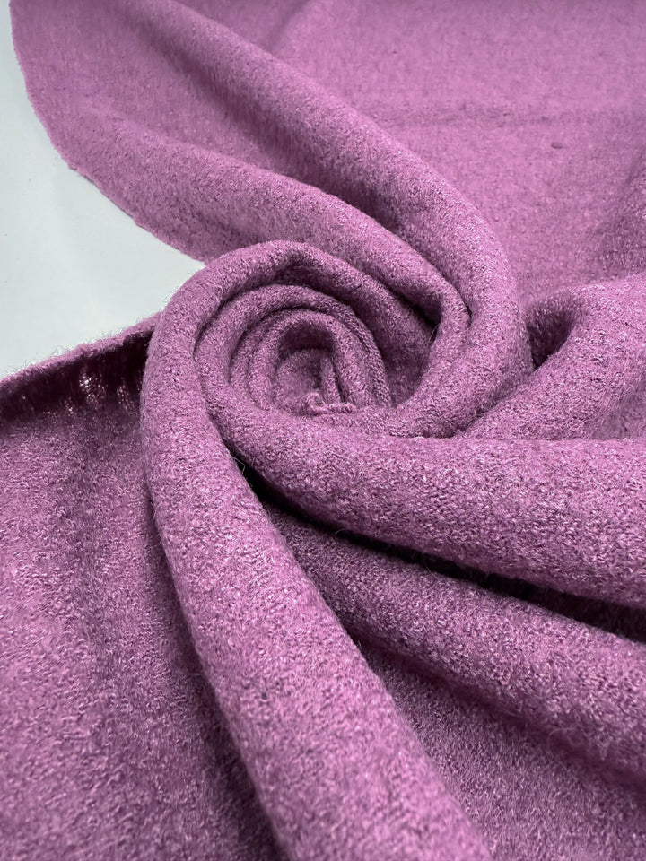 Close-up of Super Cheap Fabrics' Boiled Wool - Mauve Orchid (142cm), featuring a soft, textured surface in dusty pink, loosely twisted into a spiral to highlight its plush and cozy feel.