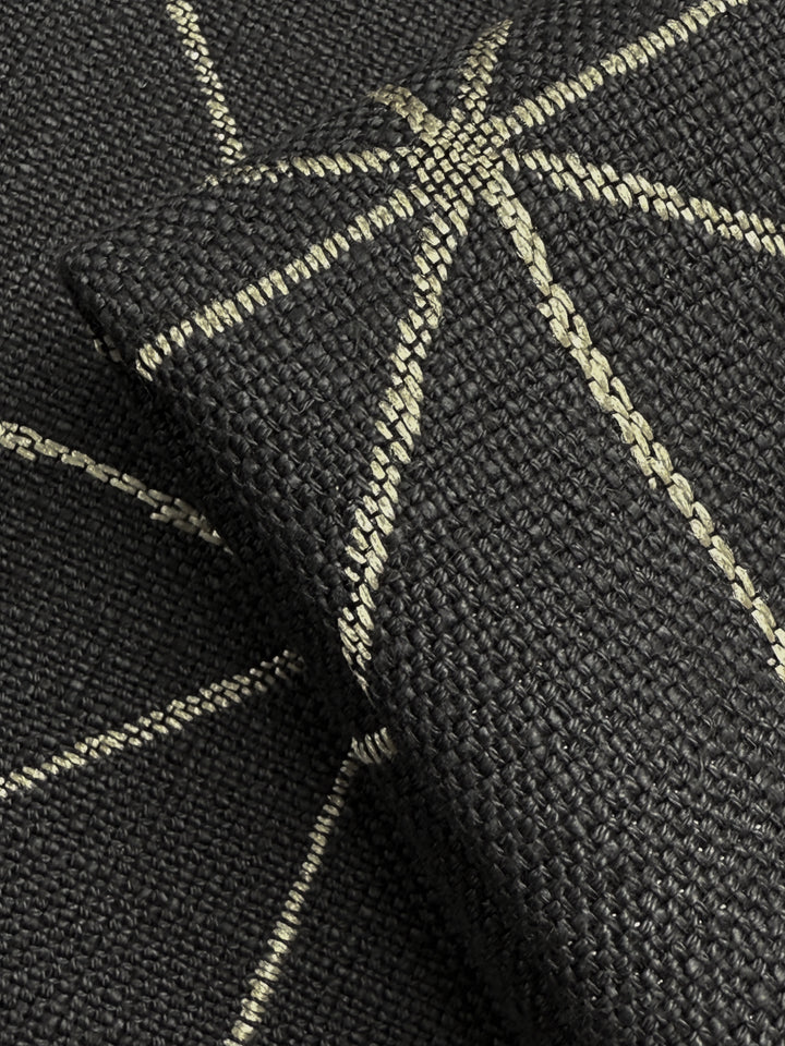 Close-up of Super Cheap Fabrics’ Linen Viscose - Quentin Coal (156cm), featuring heavy weight upholstery fabric with light geometric, star-like stitched lines. A folded piece emphasizes its rich texture and design.